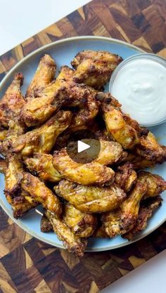 chicken wings on a plate with ranch dip in the middle, ready to be eaten