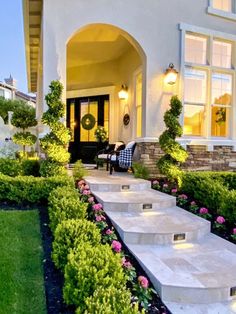 steps lead up to the front door of a house with flowers and shrubs around it