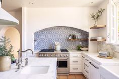 a kitchen with an oven, sink and counter tops in white marbled surfaces on the walls