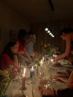 a group of people sitting around a table with wine glasses and candles in front of them