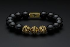 This premium brand, designer bracelet is offered with the following top quality features: 12mm Black Onyx semi-precious gemstone beads (qty. varies based on size) Handcrafted, 12mm diameter vermeil gold feature beads (qty. of 3) Handcrafted, 6 x 8 x 16mm vermeil gold Allan Marks logo bead (qty. of 1) Heavy duty, latex-free elastic stretch cord for superior strength Logo and feature beads have a base material of 925 sterling silver. Vermeil gold version is 24 karat gold plating over sterling silver. These pieces are gently oxidized to darken recessed areas to give an antique look. We will custom size your bracelet to fit your wrist. Please select wrist size by choosing either inches or centimeters from the drop-down menu. Feel free to contact us for assistance in properly measuring your wri Classic Onyx Bracelets As Gift, Luxury Black Bracelets With 8mm Beads, Luxury Black Bracelets With Polished Beads, Luxury Onyx Bracelet With 8mm Beads, Classic Onyx Bracelets With Round Beads, Luxury Beaded Bracelets With 8mm Beads, Black Onyx Bracelet, Mens Gold Bracelets, Onyx Bracelet