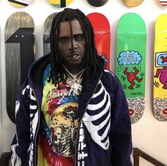 a man with dreadlocks standing in front of a wall full of skateboards