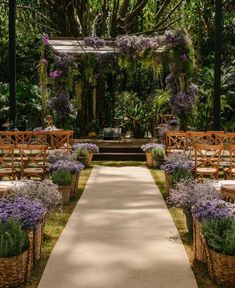 an outdoor ceremony with wooden benches and wicker baskets filled with purple flowers on the grass