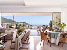 a living room filled with furniture next to a large open window overlooking the ocean and mountains