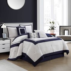 a bed with blue and white comforters in a room next to a window,