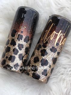 two black and gold glitter tumbles sitting on top of a white fur covered floor