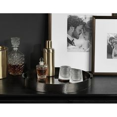 a black table topped with bottles and glasses next to a framed photo on the wall