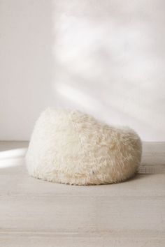 a white sheepskin bean bag sitting on top of a wooden floor next to a window