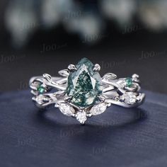 a green and white diamond ring sitting on top of a blue surface with diamonds around it