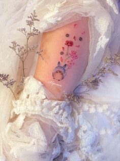 a small tattoo on the side of a woman's leg that has flowers and an animal in it