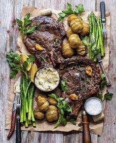 steak, potatoes and asparagus on a piece of parchment paper with knifes