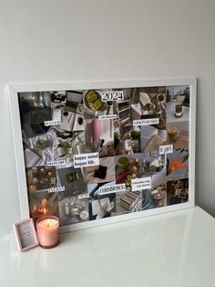 a white table topped with a candle next to a photo frame filled with pictures and candles