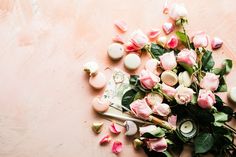 pink roses and other items are scattered around on a light colored surface with green leaves