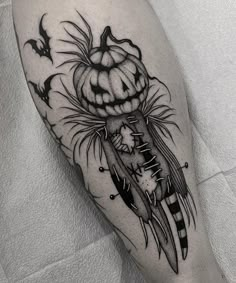 a black and white photo of a tattoo with a pumpkin on it's leg