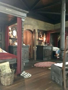 an old fashioned bedroom with wooden floors and red curtains