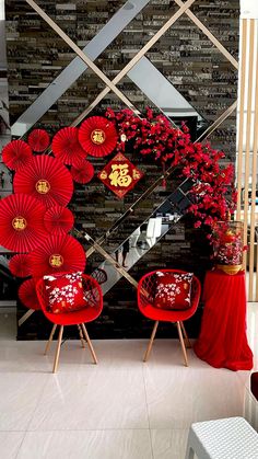 two red chairs sitting next to each other in front of a wall with decorations on it