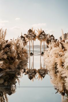 an outdoor ceremony setup with pamodia flowers and tall mirrors reflecting the water on the ground