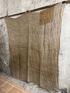 an old cloth hanging on a clothes line in front of a wall with tile flooring