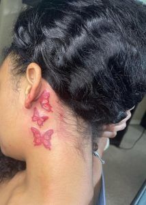 a woman with a pink butterfly tattoo on her neck