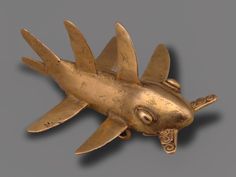 a gold brooch depicting a fish with two wings on it's back end