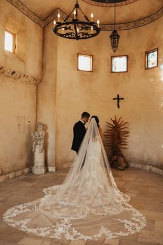 a bride and groom are standing in front of the alter with their veil blowing in the wind