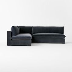 a black couch with a footstool sitting on it's side in front of a white wall