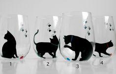 three wine glasses with black cats painted on the side and one has a blue ball in its mouth