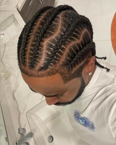 a man with long cornrows and braids on his head sitting in front of a sink