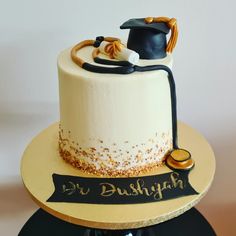 a graduation cake with gold sprinkles and a black ribbon on the top