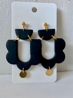 two pairs of black and gold earrings on top of a white cardigane board