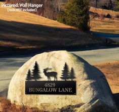 a large rock sitting in the middle of a field with trees on it and a sign that says bungalow lane