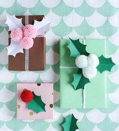 presents wrapped in green and pink paper with pom - poms