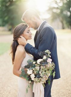 a bride and groom embracing each other in front of the sun at their outdoor wedding