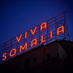 a neon sign that reads via somalia on top of a building