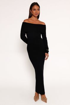 a woman wearing a black off the shoulder dress with long sleeves and high slits