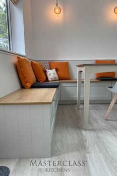 a kitchen with white cabinets and orange cushions