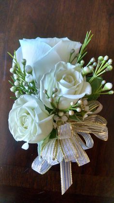 a bouquet of white roses and baby's breath on top of a wooden table