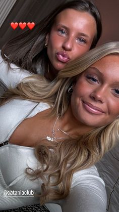 two beautiful young women posing for a photo with hearts on the wall in the background