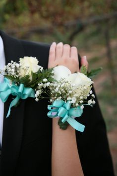 the bride and groom are wearing matching boutonnieres with white roses, baby's breath and baby's breath