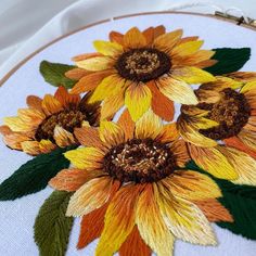 a close up of a embroidery on a white cloth with yellow and orange flowers in the center