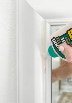 a person holding a spray bottle in front of a door with the handle on it