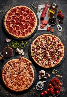 two pizzas sitting on top of pans with toppings next to each other