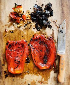 two red peppers are on a cutting board next to a knife and peppercorst