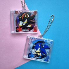 two sonic the hedge keychains on a pink and blue background