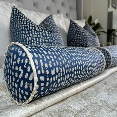 three blue and white pillows sitting on top of a bed