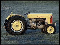 an old yellow tractor parked in the grass