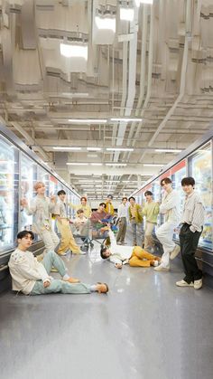 a group of people standing and sitting in front of refrigerators with food on the floor