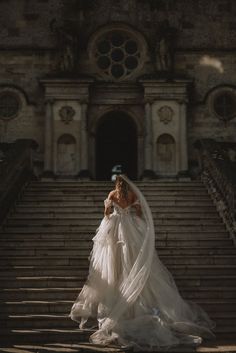 a woman in a wedding dress walking down some stairs