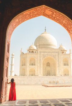 a woman in a red dress is looking out at the tajwak mosque