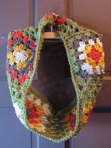 a multicolored crocheted scarf hanging from a hook on the front door